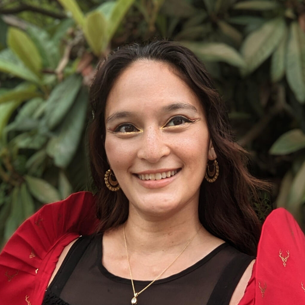 Headshot of the Author, wavy dark haired woman wearing red filipiniana butterfly sleeves and a black shirt